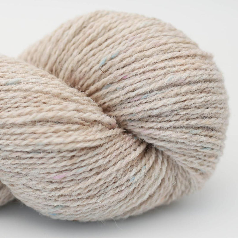 Skein of yarn with a muted speckled pattern on a light beige background Beara Irish wool and UK alpaca tweed dk, worsted or aran weight yarn by Hey Mama Wolf 
